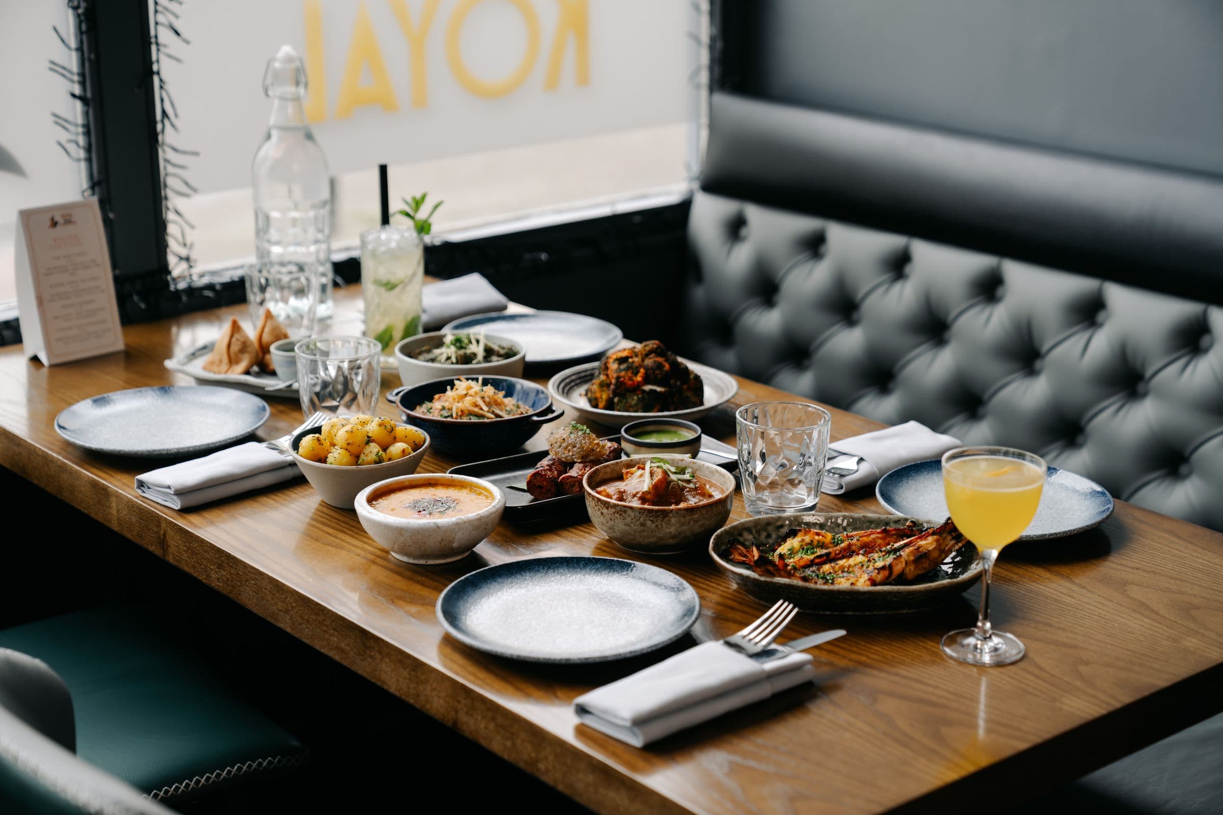 A spread of dishes on a table by the window at Koyal Indian Restaurant in Surbiton
